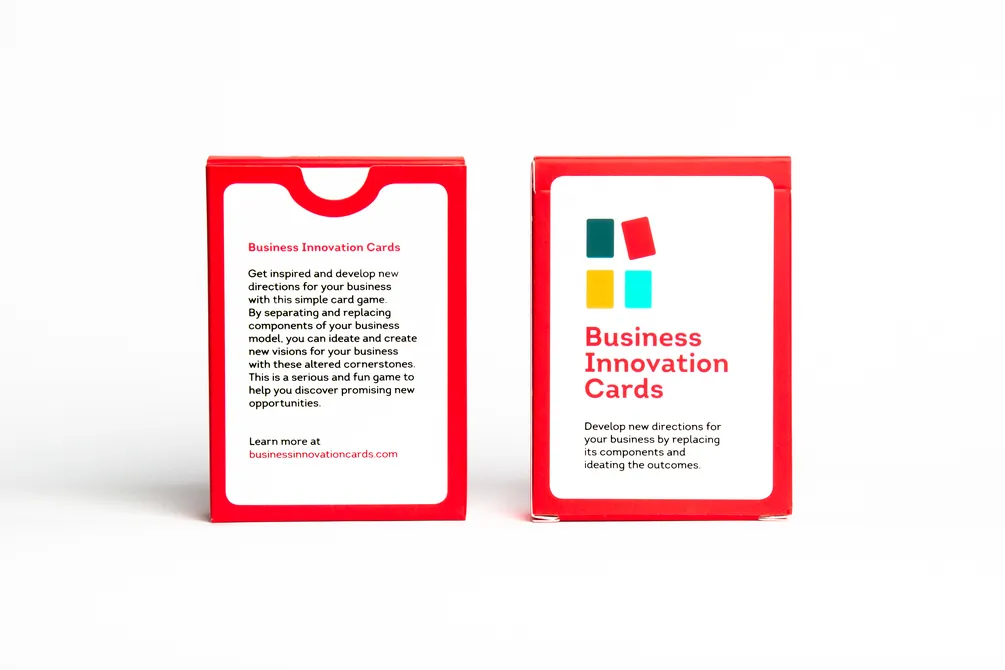 Packaging of the game, a cardboard box with red edges. The front has a logo consisting of 4 colored cards, the game's title 'Business Innovation Cards' and the text 'Develop new directions for your busiess by replacing it's components and ideating the outcomes.'.